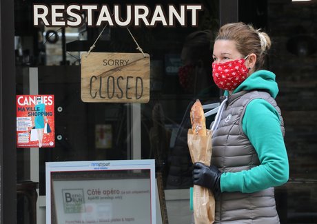 Fermeture commerce restaurant. Une femme portant un masque et une baguette passe devant un restaurant fermé à cause de l'épidémie de coronavirus, le 16 avril 2020 à Cannes