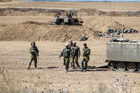 Des soldats israeliens marchent a cote d’un vehicule militaire pres de la frontiere avec gaza