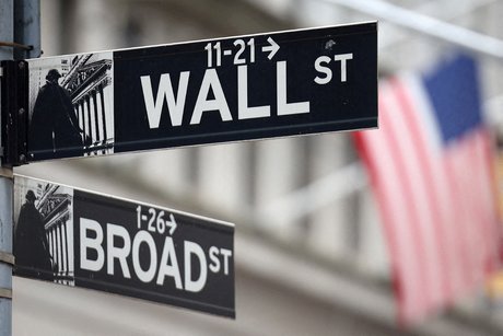 Un panneau wall street est suspendu devant un drapeau americain a l'exterieur de la bourse de new york (nyse) a new york