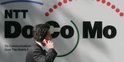 Un homme avec un téléphone passe devant le logo de NTT DoCoMo, l'opérateur mobile numéro 1 au Japon