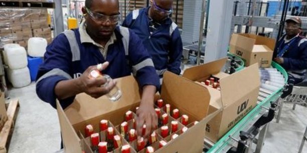 Les employés emballent des bouteilles à partir d'un tapis roulant à l'usine East African Breweries Limited à Nairobi, au Kenya, le 6 avril 2018.