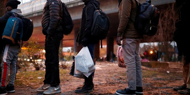 Photo d'illustration: le 31 janvier 2019, des migrants réfugiés emportent leurs effets personnels pendant l'opération d'évacuation par la police d'un camp de fortune installé sous une voie du périphérique parisien, au niveau de la Porte de la Villette.