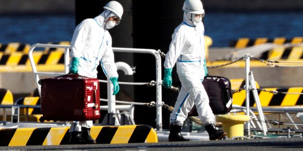 Des agents en équipements de protection sur le port de Yokohama, au sud de Tokyo (Japon), le 5 février se rendent auprès des passagers du bateau de croisière Diamond Princess où quelque dix touristes ont été déclarés contaminés par le coronavirus.
