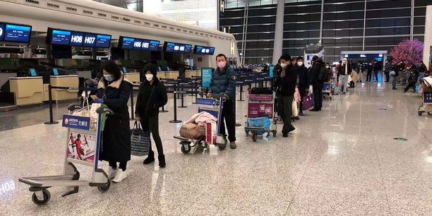 Le le 7 février 2020, à l'aéroport international de Wuhan Tianhe (Chine), des passagers font la queue pour monter à bord d'un avion-cargo affrété par le Département d'État américain pour évacuer de Chine les ressortissants américains et canadiens à cause du nouveau coronavirus.