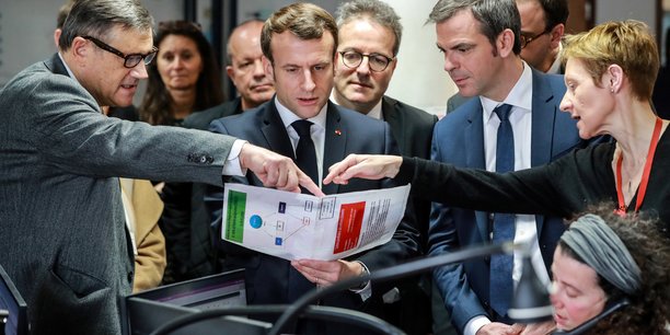 Le président français Emmanuel Macron et le ministre français de la Santé et de la Solidarité Olivier Veran écoutent le professeur Pierre Carli, directeur des services d'urgence SAMU-SMUR de l'hôpital Necker, lors d'une visite au centre d'appels SAMU-SMUR de l'hôpital axée sur l'épidémie de coronavirus COVID-19, à Paris, 10 mars 2020.