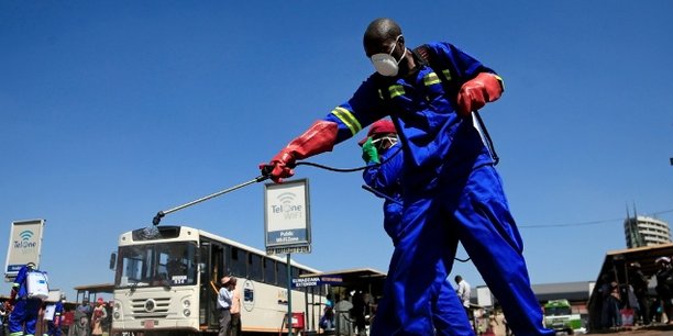 Des agents du service municipal d'hygiène désinfectent une place publique près d'une station de bus, le 1er avril 2020 à Harare, au Zimbabwe.