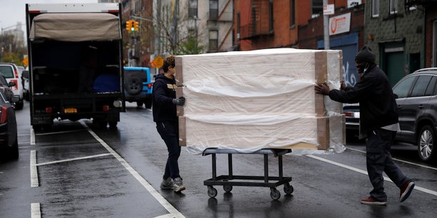 Des employés déplacent une pile de nouveaux cercueils d'un entrepôt vers un camion de livraison, le 24 avril 2020, dans le quartier de Brooklyn, à New York, extrêmement touchée par la pandémie de coronavirus (COVID-19).