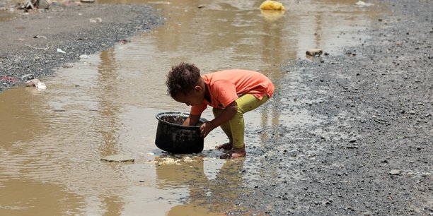 Yémen : un enfant nettoie une marmite avec de l'eau de pluie dans un bidonville de la capitale Sanaa, le 26 juillet 2020.