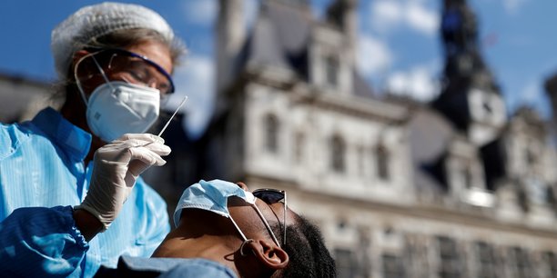 Un agent de santé, portant combinaison de protection et masque facial, se prépare à administrer un écouvillon nasal à un patient sur un site de test de la maladie à coronavirus (Covid-19) installé place de l'Hôtel-de-Ville, devant la mairie de Paris, le 2 septembre 2020.