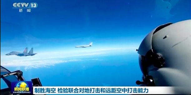 Capture d'écran d'images de la télévision chinoise transmises par Reuters et décrites comme un exercice de déploiement, le 7 samedi 7 août 2022, de forces aériennes de l'Armée populaire de libération (APL) de Chine autour de l'île de Taiwan dans le cadre de manœuvres militaires. La photo montre le pilote d'un avion de combat chinois non identifié le regard tourné vers ses compagnons de vol: un chasseur J-16 et, au loin, un Xian H-6 (copie du bombardier soviétique Tupolev Tu-16.