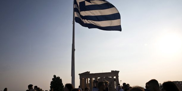 Le drapeau grec flotte au vent au-dessus de touristes visitant le site archeologique de l'acropole a athenes, en grece[reuters.com]