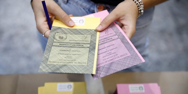 Une personne tient des bulletins de vote dans un bureau de vote[reuters.com]