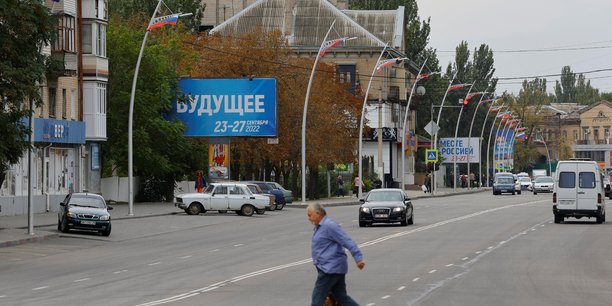 Un homme marche devant des panneaux au sujet d'un referendum sur le rattachement a la russie des regions ukrainiennes controlees par la russie[reuters.com]