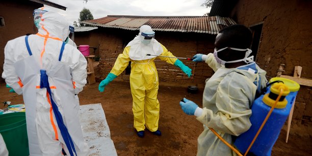Un travailleur de la sante decontamine son collegue apres etre entre dans la maison d'une femme soupconnee d'avoir  decede de la fievre ebola[reuters.com]