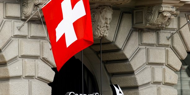 Le drapeau national suisse flotte au-dessus du logo de la banque suisse credit suisse a zurich[reuters.com]