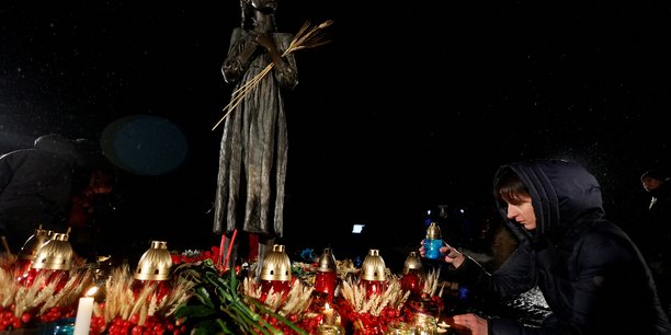 Une femme place une bougie devant un monument aux victimes de l'holodomor[reuters.com]