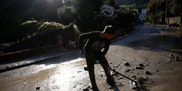 Une personne nettoie une rue couverte de boue, suite a un glissement de terrain sur l'ile italienne d'ischia[reuters.com]