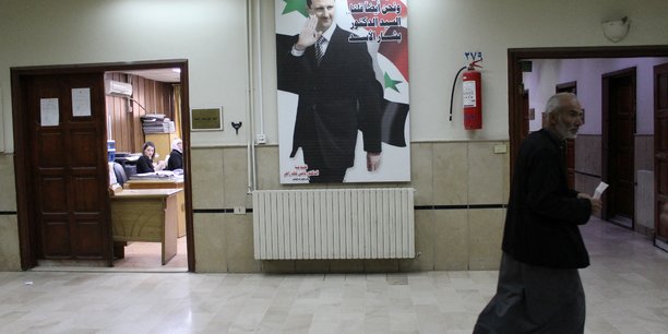 Un homme passe devant une photo du president syrien bashar al-assad a l'interieur de l'hopital ibn al-nafis a damas[reuters.com]