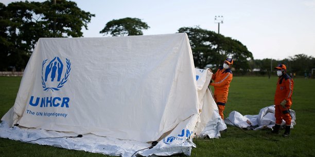 Des employes de la defense civile colombienne montent des tentes pour un camp qui servira d'abri aux migrants[reuters.com]