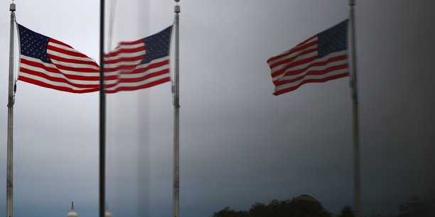 Le capitole des etats-unis et les drapeaux americains se refletent dans une fenetre a washington[reuters.com]