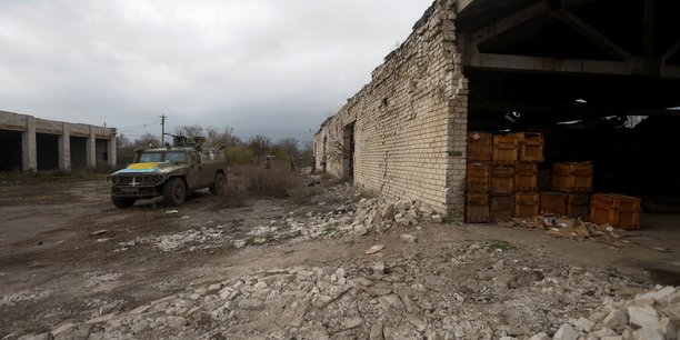 Des membres des services ukrainiens marchent vers un vehicule blinde de transport de troupes russe precedemment capture dans le village de blahodatne, dans la region de kherson[reuters.com]