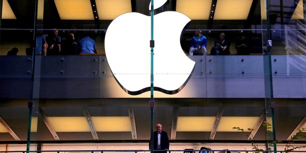 Un client se tient sous un logo apple illumine alors qu'il regarde par la fenetre du magasin apple situe dans le centre de sydney[reuters.com]