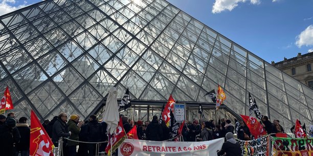 Des manifestants portant des drapeaux cgt et sud culture solidaires se tiennent devant la pyramide du louvre[reuters.com]