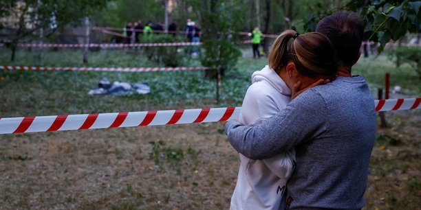 Photo de residents locaux pres du corps d'une personne tuee lors d'une frappe de missile russe a kyiv[reuters.com]