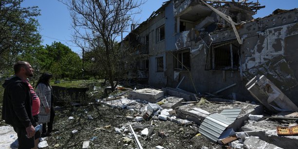 Photo des residents locaux qui se tiennent a cote d'un immeuble fortement endommage par une frappe de missiles russes dans la ville de pidhorodne, au nord de dnipro[reuters.com]