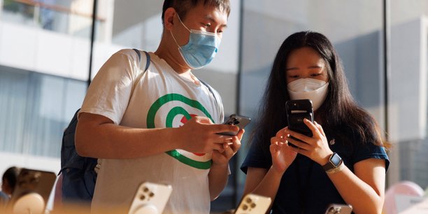 Un client et une vendeuse regardant un iphone dans un apple store a pekin[reuters.com]