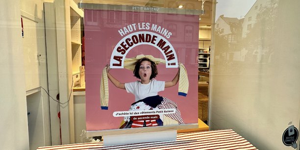Une affiche apposée en vitrine informe les clients sur l'offre de seconde main, dans un magasin Petit Bateau à Strasbourg.
