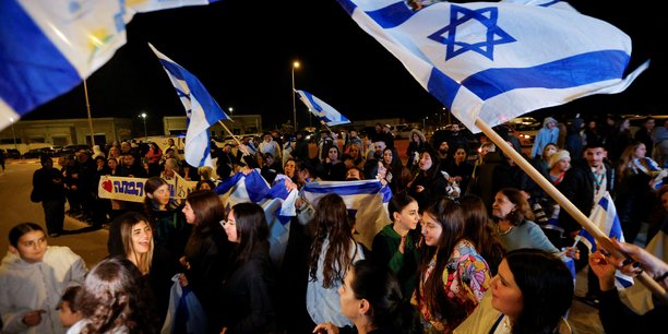 Des personnes brandissent des drapeaux israeliens a ofakim, en israel, apres la liberation des otages captures lors de l'attaque du 7 octobre par le hamas[reuters.com]