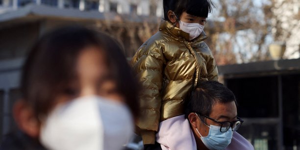 Un homme porte un enfant devant un hopital, en chine[reuters.com]