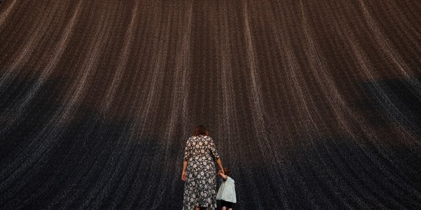 Une femme tient la main d'un bebe alors qu'ils profitent tous deux de la cascade de l'expo a la cop28, a dubai[reuters.com]