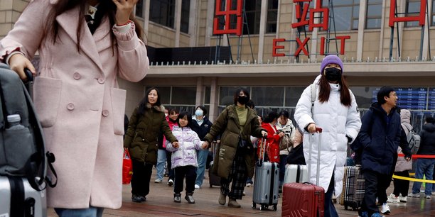Des voyageurs marchent avec leurs bagages a l'exterieur de la gare de pekin pendant la fete du printemps[reuters.com]
