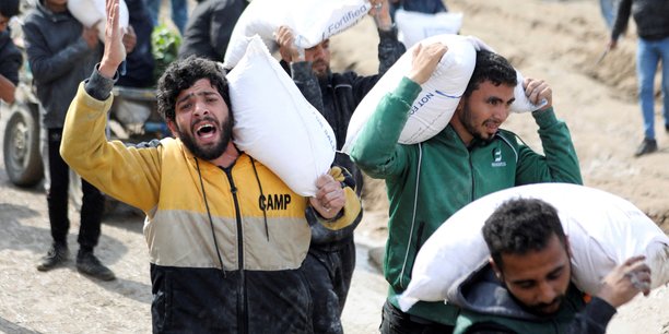 Des palestiniens transportent des sacs de farine recuperes dans un camion humanitaire a gaza[reuters.com]