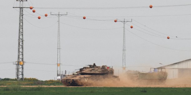 Photo d'un un char israelien qui tire un vehicule blinde de transport de troupes (apc) pres de la frontiere entre israel et gaza[reuters.com]