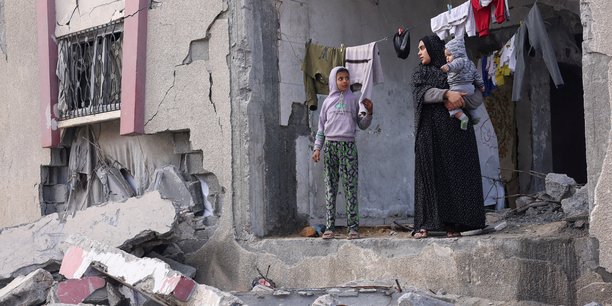 Une palestinienne tient son enfant dans les bras alors qu'elle se tient devant une maison endommagee par les frappes israeliennes, a rafah[reuters.com]