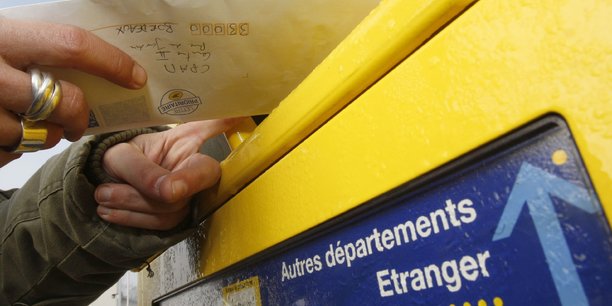 Un homme poste une lettre dans la boite aux lettres de la poste a margaux[reuters.com]