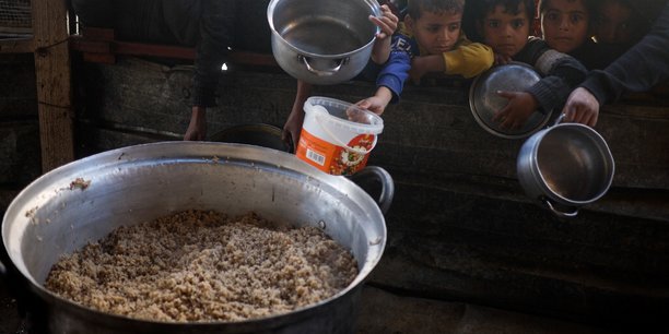Des enfants palestiniens attendent de recevoir de la nourriture preparee par une cuisine caritative dans un contexte de penurie alimentaire, a rafah[reuters.com]