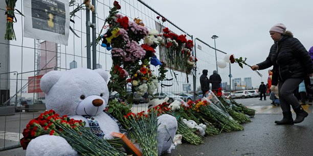 Une femme depose des fleurs sur un memorial improvise en l'honneur des victimes d'un attentat a la salle de concert crocus city hall, dans la banlieue de moscou[reuters.com]