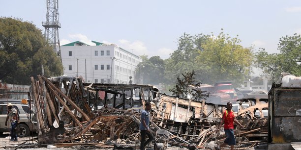 Des gens passent devant les restes de vehicules incendies par des gangs, a port-au-prince[reuters.com]