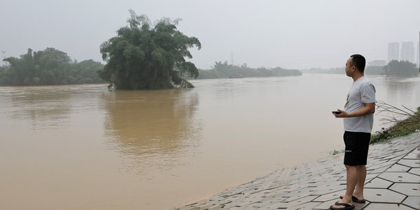 Photo d'un habitant pres d'une riviere en crue suite a de fortes pluies a qingyuan[reuters.com]