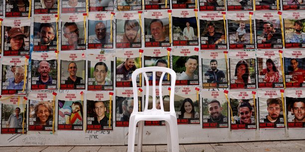 Une chaise est laissee devant des affiches avec des photos d'otages[reuters.com]