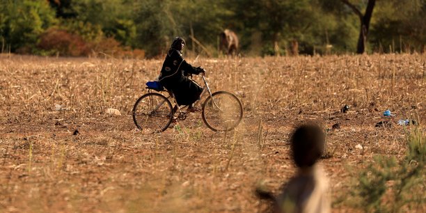 Photo d'archives: un enfant qui a fui avec ses parents les attaques de militants armes dans la region du sahel observe une femme a velo dans un camp de personnes deplacees au burkina faso[reuters.com]
