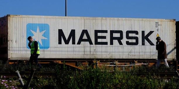 Des travailleurs parlent sur leur telephones portables, alors qu'un conteneur maersk est transporte par un train, pres du port de barcelone[reuters.com]