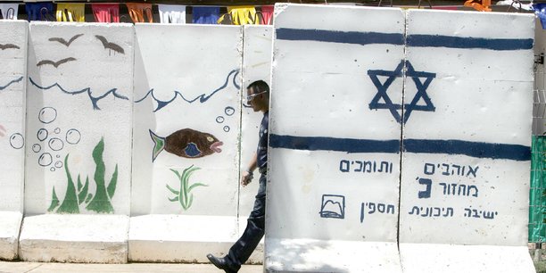 Un colon israelien marche entre des murs de protection en beton dans la colonie de ganim, en cisjordanie[reuters.com]
