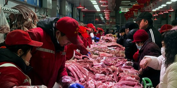 Des vendeurs de porc s'occupent des clients dans un marche a pekin[reuters.com]