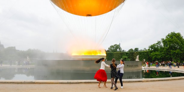 Des jeunes visiteurs jouent autour de la vasque olympique installée dans le Jardin des Tuileries, à Paris.