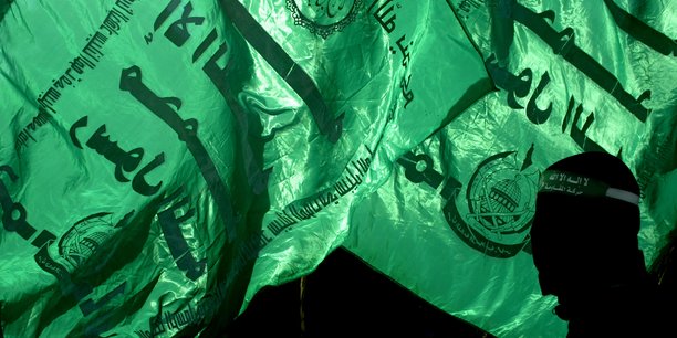 Un membre du hamas devant des drapeaux du groupe a gaza[reuters.com]